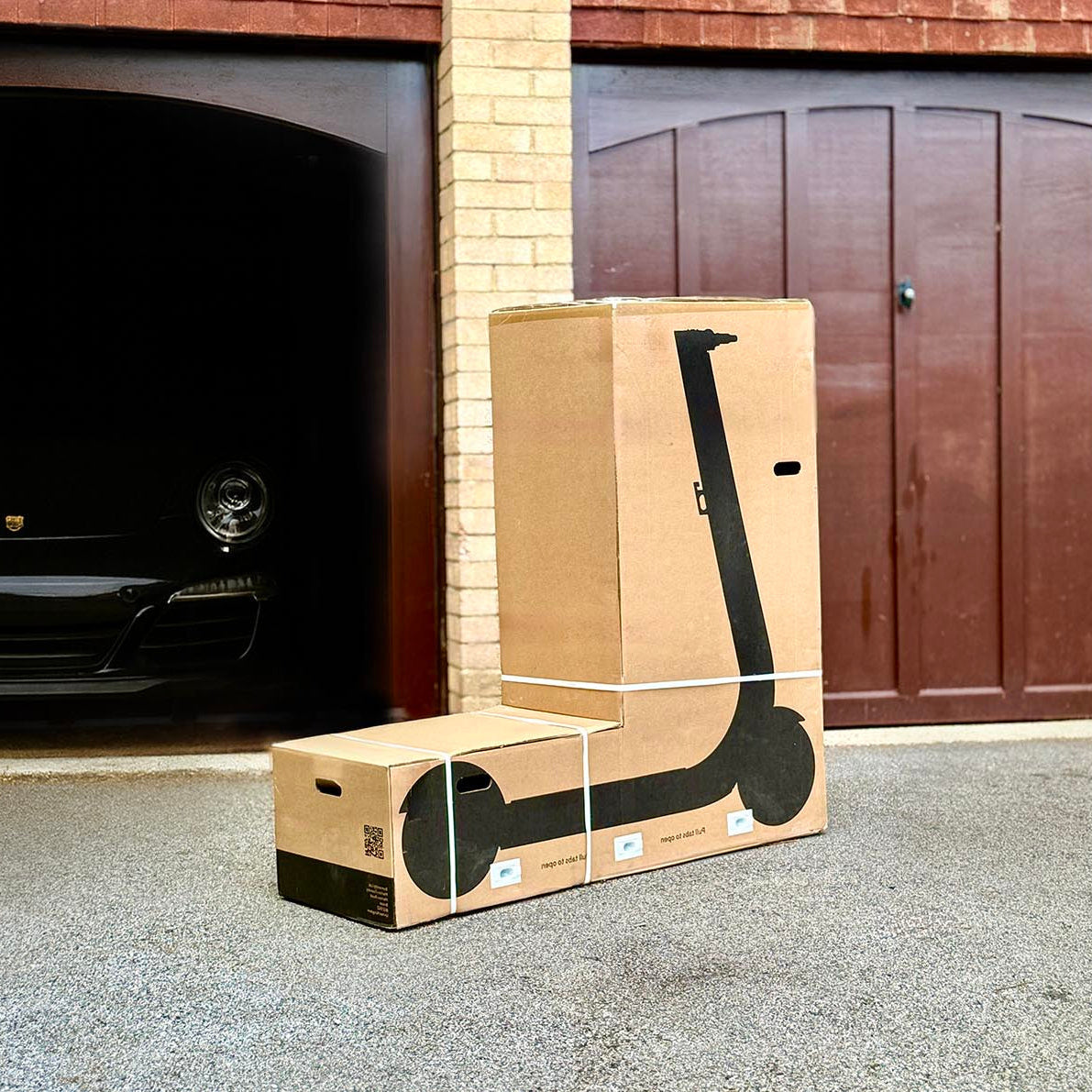 Box with a scooter on the ground in front of a garage