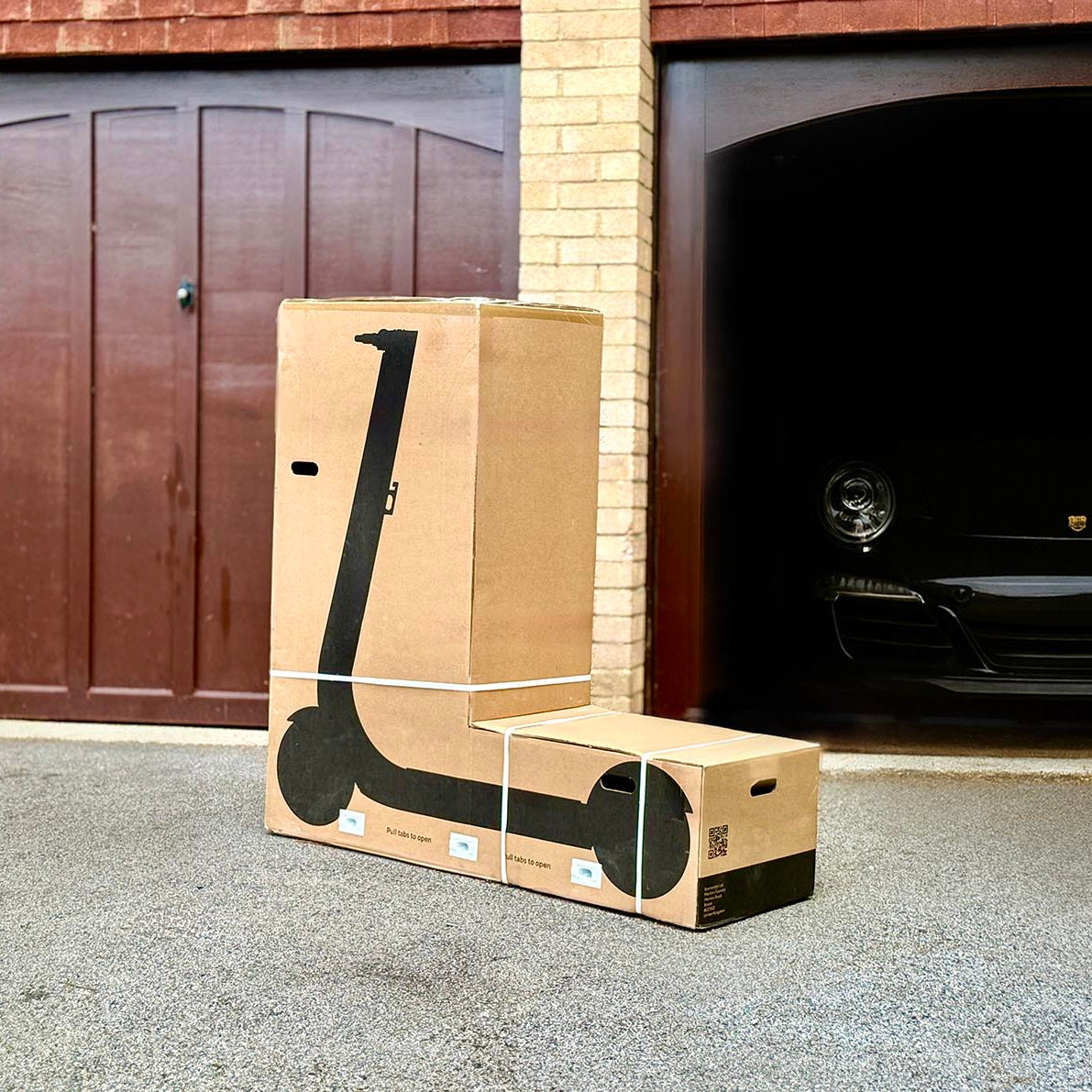 Box with a scooter on the ground in front of a garage