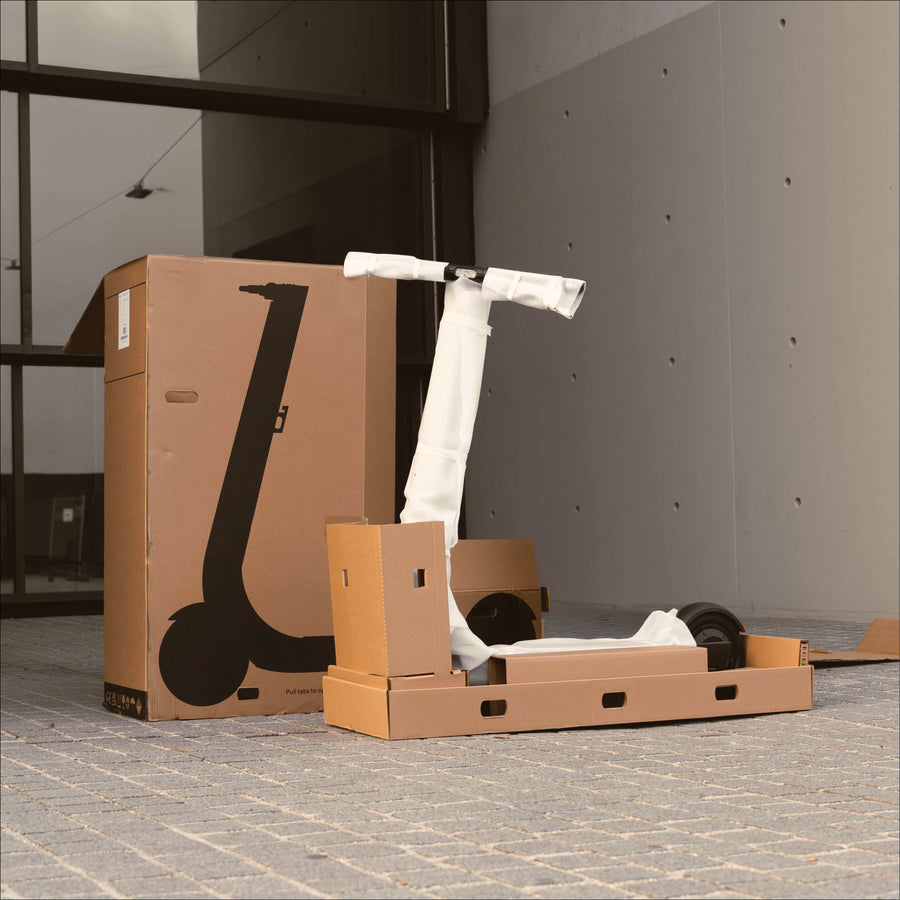 E-scooter partially assembled on cardboard boxes with its packaging box in the background.
