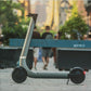 Electric scooter on a sidewalk with people and greenery in the background