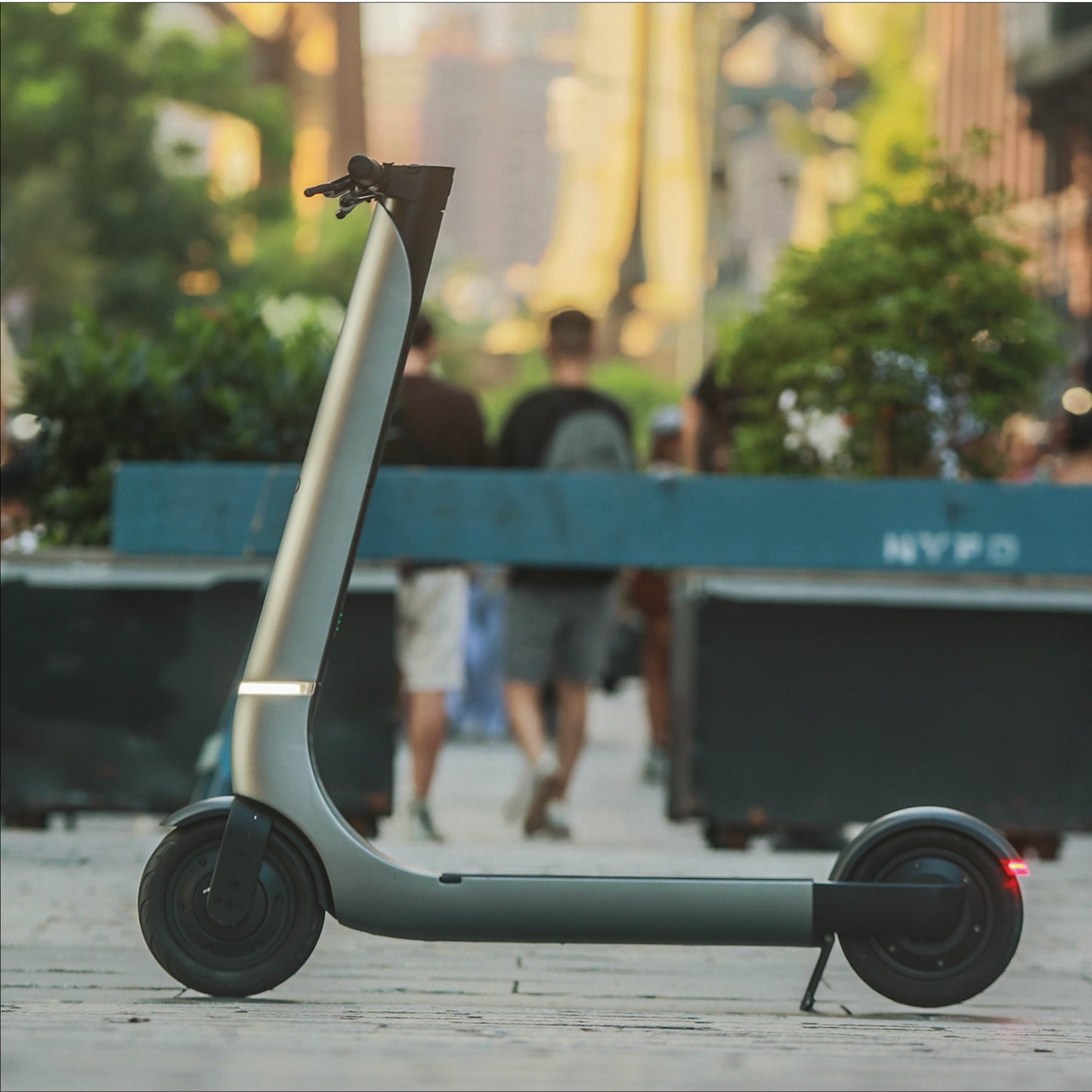 Electric scooter on a sidewalk with people and greenery in the background