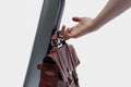 Hand reaching to grab a brown leather bag from scooter hooks.