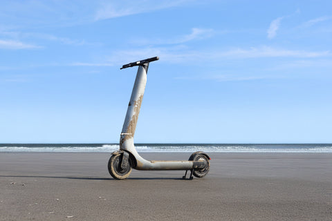 Wet and sandy scooter on a beach with a clear blue sky
